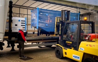 Standby diesel generator being unloaded by forklift from the back of a lorry