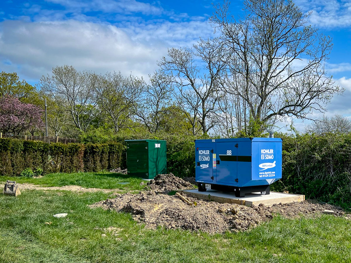 Kohler-SDMO generator positioned on concrete pad in a garden. Residential generator install