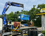 Generator being lifted off flatbed trailer in to position